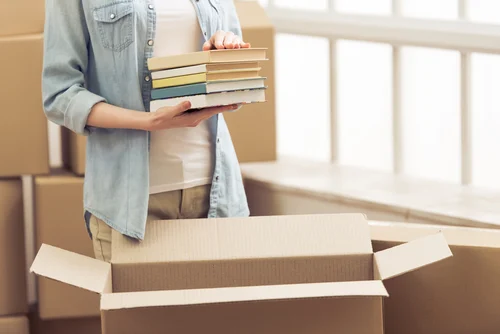Cropped,image,of,attractive,young,woman,moving,,packing,books,in