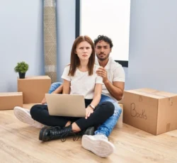 Young,couple,using,laptop,at,new,home,skeptic,and,nervous,